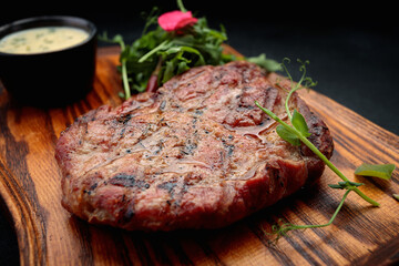 Pork neck steak with sauce and arugula, on a wooden board