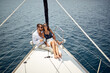 © luckybusiness - A young couple sitting on the bow of the yacht and enjoying a ride on the sea. Summer, sea, vacation, relationship