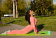 © lashkhidzetim - Young beautiful black woman in pink leggings and a top practicing yoga in a city park.