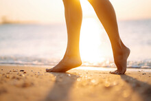 Close Up Of A Female's Bare Feet Walking At A Beach At Sunset. Summer Time. Travel, Weekend, Relax And Lifestyle Concept.