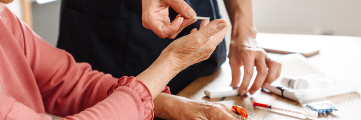 A close-up view of the doctor measuring blood glucose level to her elderly patient