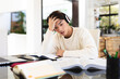© Wavebreak Media - Stressed asian teenage boy wearing headphones with head in hand studying on table at home