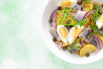 Wall Mural - Herring and boiled potato salad with egg, capers and red onion. Top view