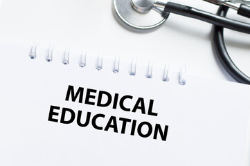 Wall Mural - The text MEDICAL EDUCATION on a notebook on a white table next to a stethoscope, a medical concept