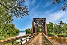 Beneath A Blue Sky With White Clouds On A Summer Day In Wisconsin, An Old Train Trestle Has Been Converted To Carry Only Hikers And Bikers Across A Mississippi Backwater On The Great River Trail.