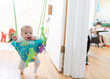 © Maria Manco/Stocksy - happy baby in doorway jumper with brother in background