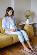 © ZHPH Production/Stocksy - Woman with laptop sitting on the sofa at home