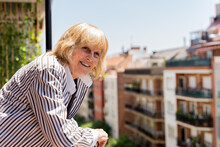 Happy Senior Woman Relaxing In Balcony At Home