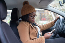 Black Woman Using Smartphone In The Car, Wearing Winter Clothes