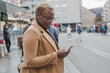 © Anna Berkut/Stocksy - black woman using smartphone on bus stop, commuter, transportation