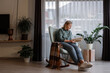 © Milles Studio/Stocksy - Woman reading book on rocking chair