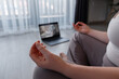 © Milles Studio/Stocksy - Crop female meditating during online yoga lesson