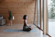 © Milles Studio/Stocksy - Woman meditating near window at home
