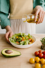 Woman Adding Oil To Salad