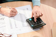 © Martí Sans/Stocksy - Crop person checking bills and using calculator