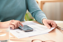 Crop Woman Counting Expenses On Calculator At Home