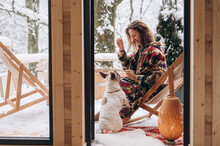 Woman With Dog Admiring Nature On Terrace Of A Frame Hut