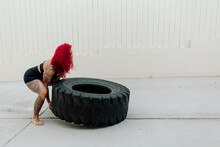 Muscular Woman With Red Hair Lifting Tire