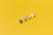 © Yaroslav Danylchenko/Stocksy - Four quail eggs lying in diagonal line on yellow background