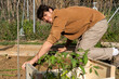© Alba Vitta/Stocksy - portrait of Young happy man planting vegetable plants on garden