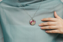 Close Up Of Female Hands Holding Floral Epoxy Necklace