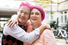 Man with pink hair kissing his woman 