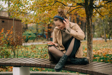 Woman Sitting On A Bench In Autumn Park