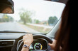 © DG PhotoStock - Unrecognizable female driver using left hand grabs on the steering wheel while driving on the road.