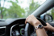 © DG PhotoStock - Unrecognizable female driver using left hand grabs on the steering wheel while driving on the road.