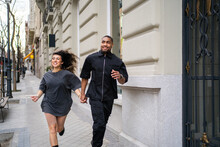 Young Couple Running On The Street.