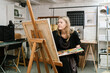 © Ezequiel Giménez/Stocksy - Craftswoman painting on easel in workshop