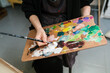 © Ezequiel Giménez/Stocksy - Crop painter with colorful palette in art studio