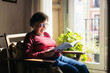 © Pedro Merino/Stocksy - Elderly woman reading a book at home