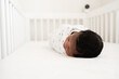© Alison Winterroth/Stocksy - Baby laying in crib with camera watching