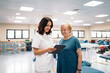 © Santi Nuñez/Stocksy - Physiotherapist and patient using tablet in clinic