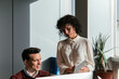 © David Prado/Stocksy - Happy colleague couple using computer in office desk