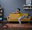 © Elena Kharichkina/Stocksy - A woman in headphones does exercises at home