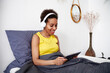 © Elena Kharichkina/Stocksy - A girl uses a tablet in bed