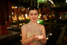Young Asian Woman Holds A Small Lantern Into Water In Xishuangbanna.
