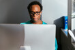 © David Prado/Stocksy - Cheerful black man working with computer at office in a sunny day