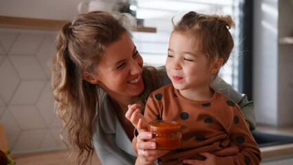 Wall Mural - Happy young mother with little daughter in kitchen eating together at home.