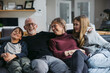 © Ameris Photography Inc./Stocksy - Grandparents and grandkids cudding on the couch.