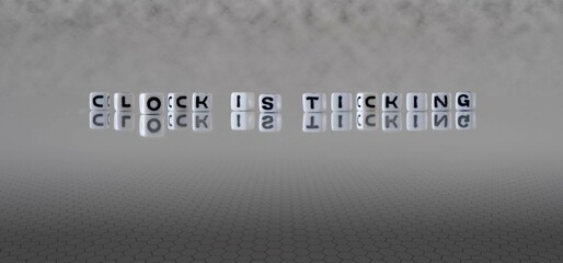 clock is ticking word or concept represented by black and white letter cubes on a grey horizon background stretching to infinity