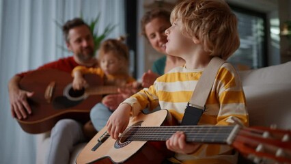 Wall Mural - Little children with parents playing the guitar on sofa at home.