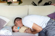 © Albert Martinez/Stocksy - Father kissing baby on couch