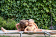 © Albert Martinez/Stocksy - Sister kissing little brother on camp bed