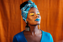 Woman With African Print Head Band And Creative Makeup Over Orange 