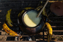 A Top View Of A Black Clay Pot And Bananas On A Grill On The Ground 