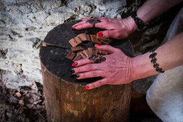 Wall Mural - Female hands holding old wooden runes in dark medieval setting. Pile of wooden chips with different symbols used to predict future and get wisdom.