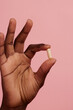 © Anna Tabakova/Stocksy - Dark skinned hand holding a pill